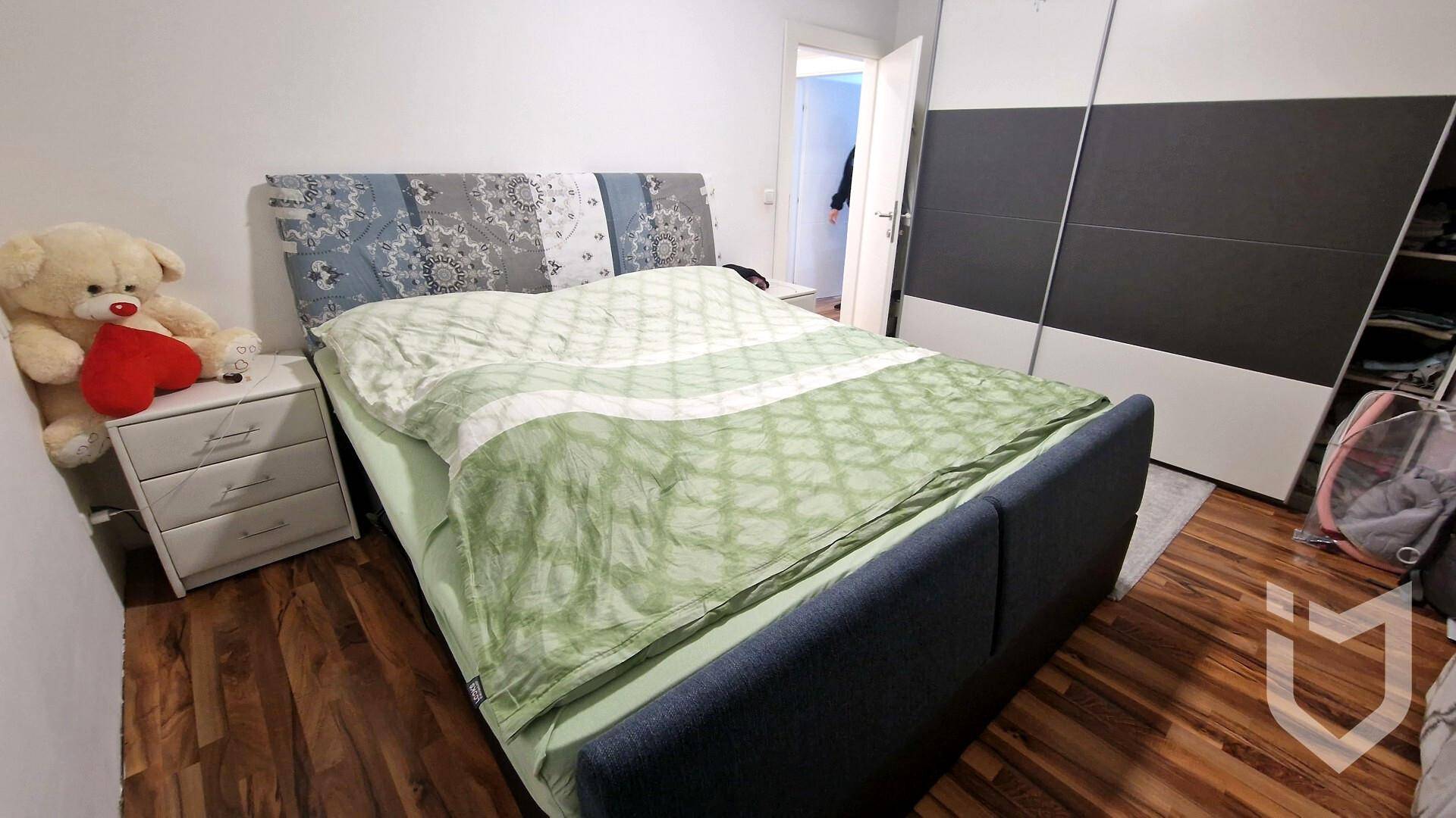 Schlafzimmer mit Doppelbett, Nachttisch und großem Schiebetürenschrank.