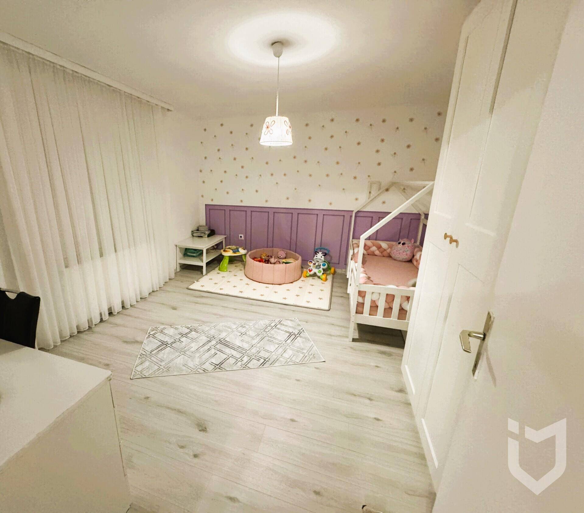 Helles Kinderzimmer mit kleinem Bett, Spielbereich und weißem Kleiderschrank.