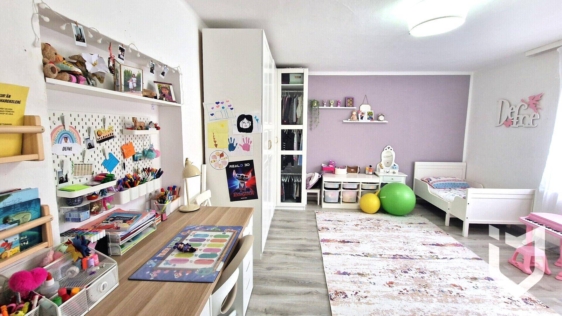 Helles Kinderzimmer mit Bett, Schreibtisch und farbenfroher Dekoration an der Wand.