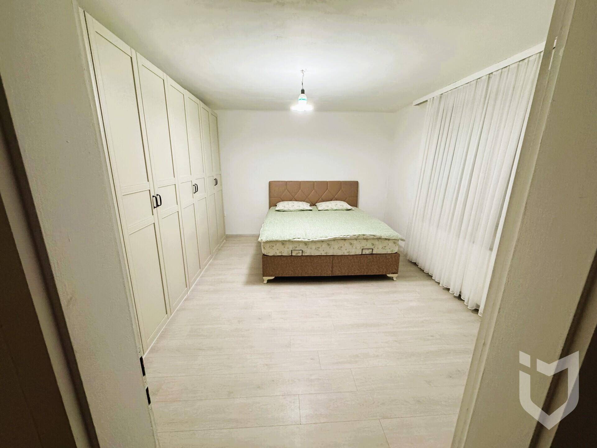 Schlafzimmer mit Doppelbett, weißen Kleiderschränken und hellem Laminatboden.