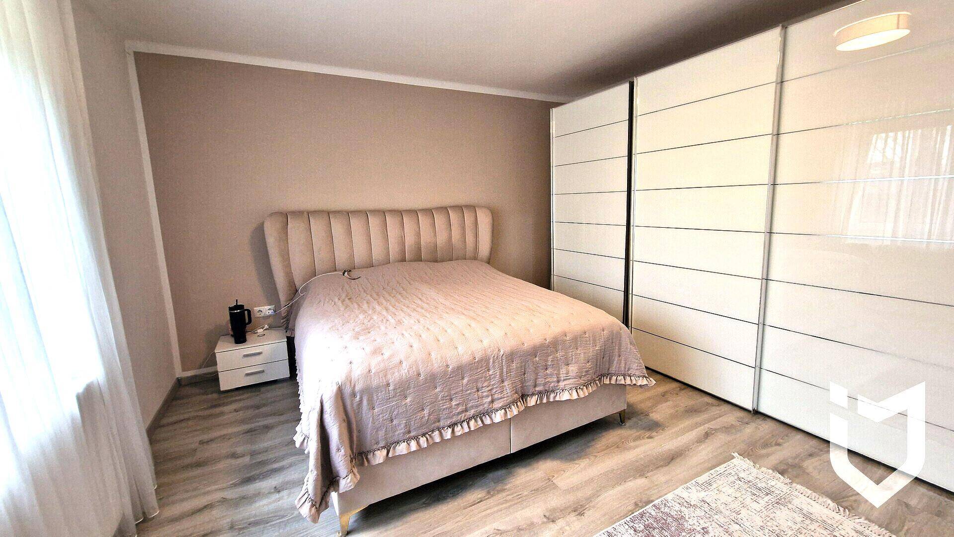 Gemütliches Schlafzimmer mit Doppelbett, großen weißen Einbauschränken und hellem Laminatboden.