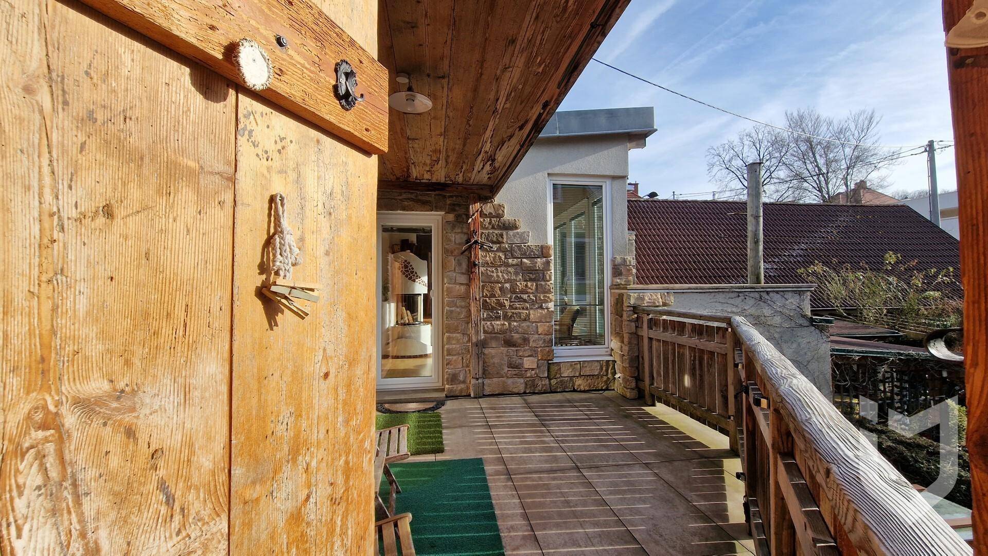Rustikaler Holzbalkon mit Steinmauer und Blick auf die Umgebung.