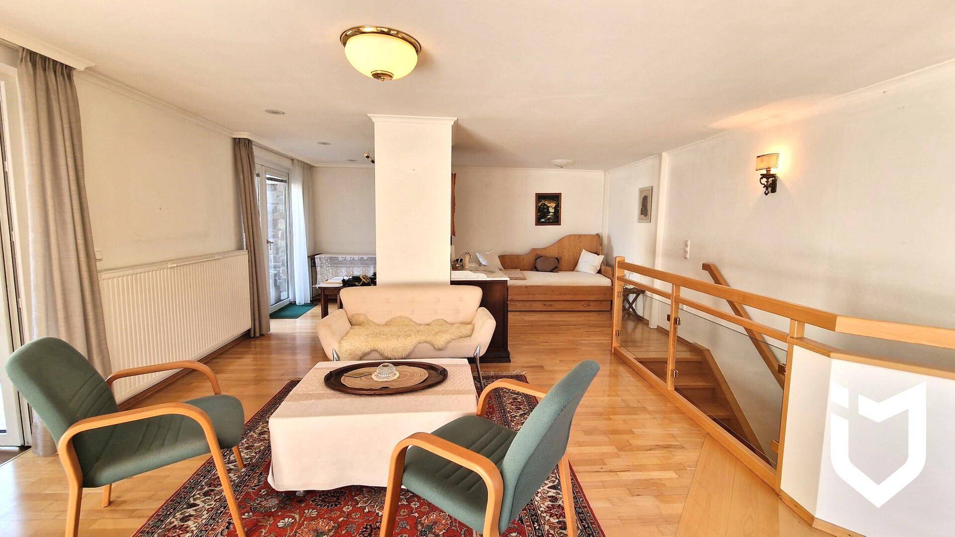 Geräumiger Wohnbereich mit Holzboden, Sofa und Treppe zum oberen Stockwerk.