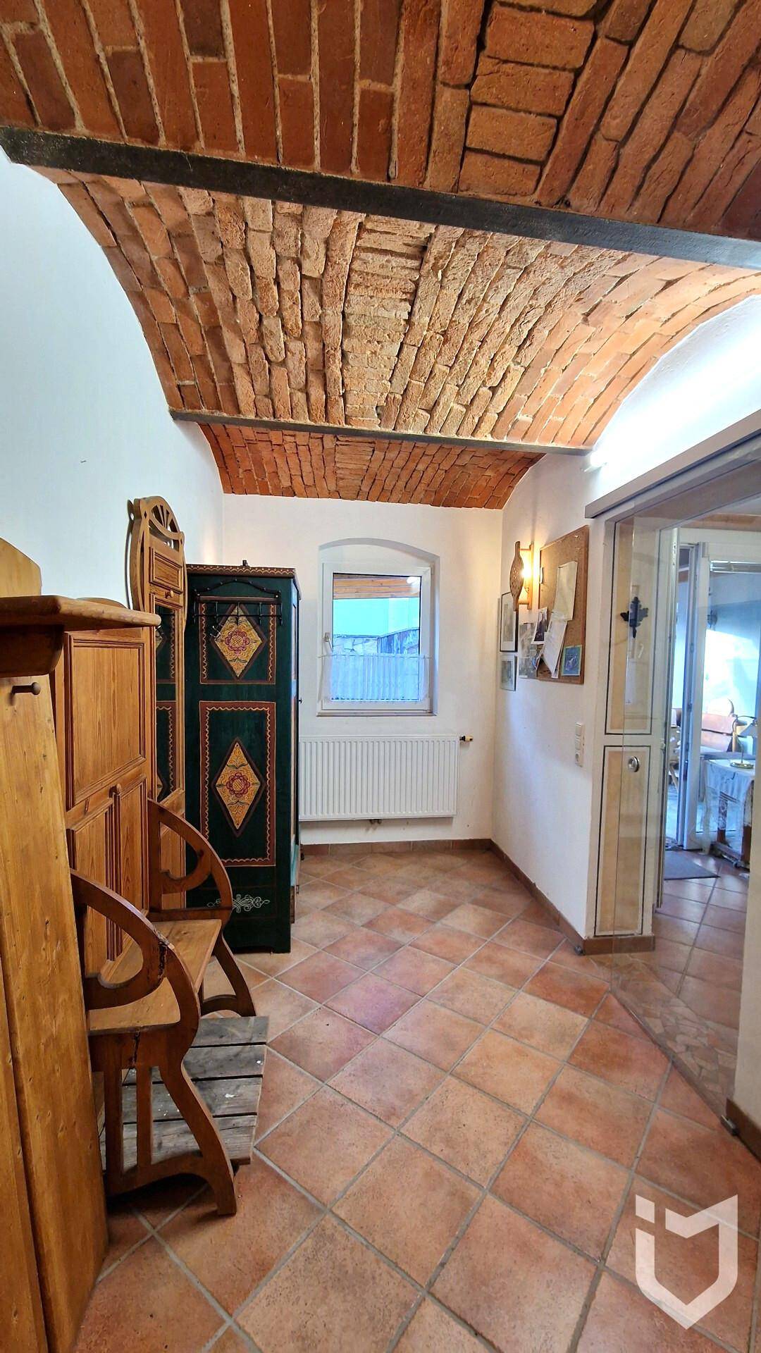 Flur mit Terrakotta-Fliesenboden, Gewölbedecke aus Ziegeln und traditionellen Möbeln.