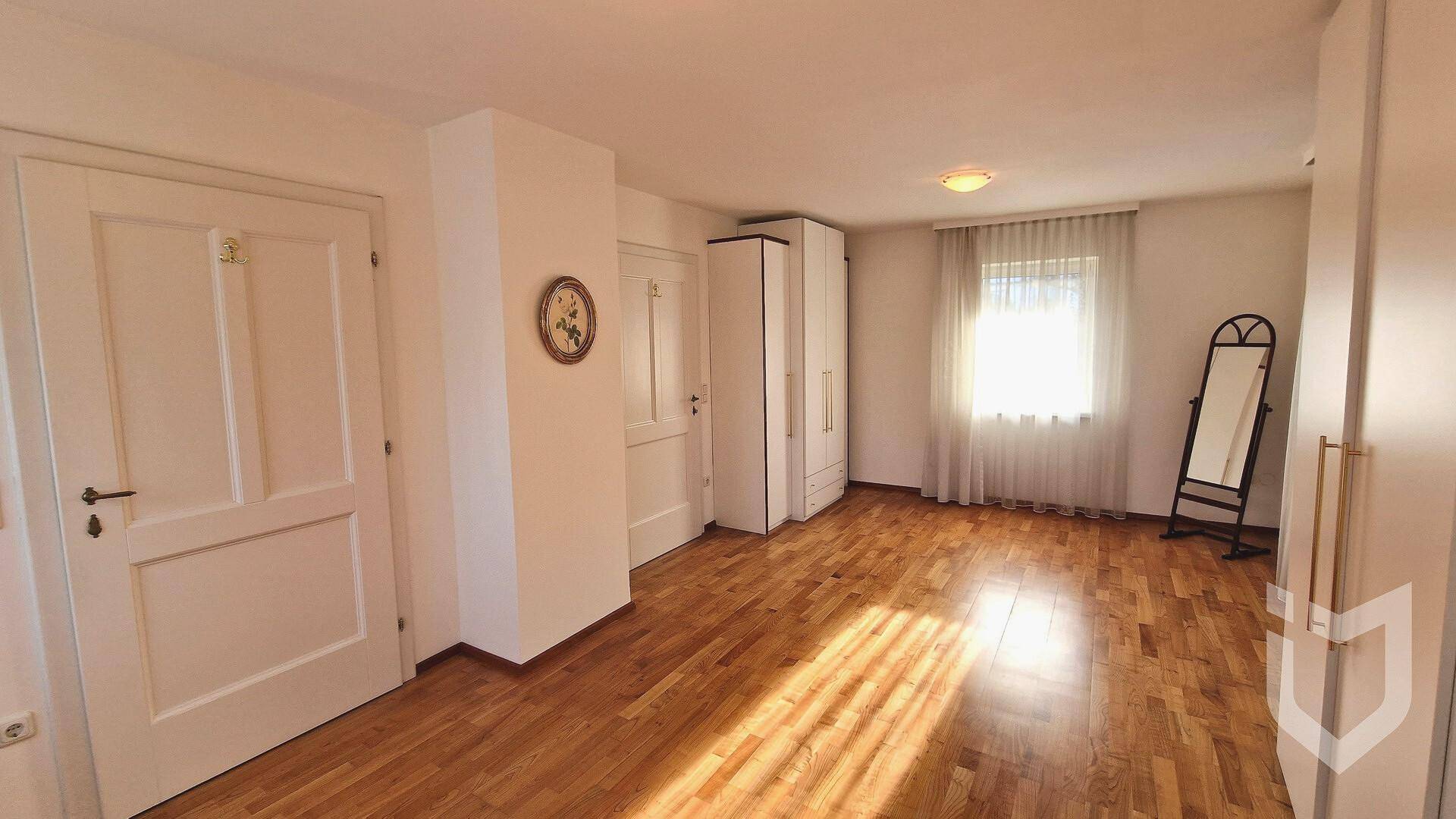 Geräumiges Schlafzimmer mit Holzboden, großem Fenster und viel natürlichem Licht.