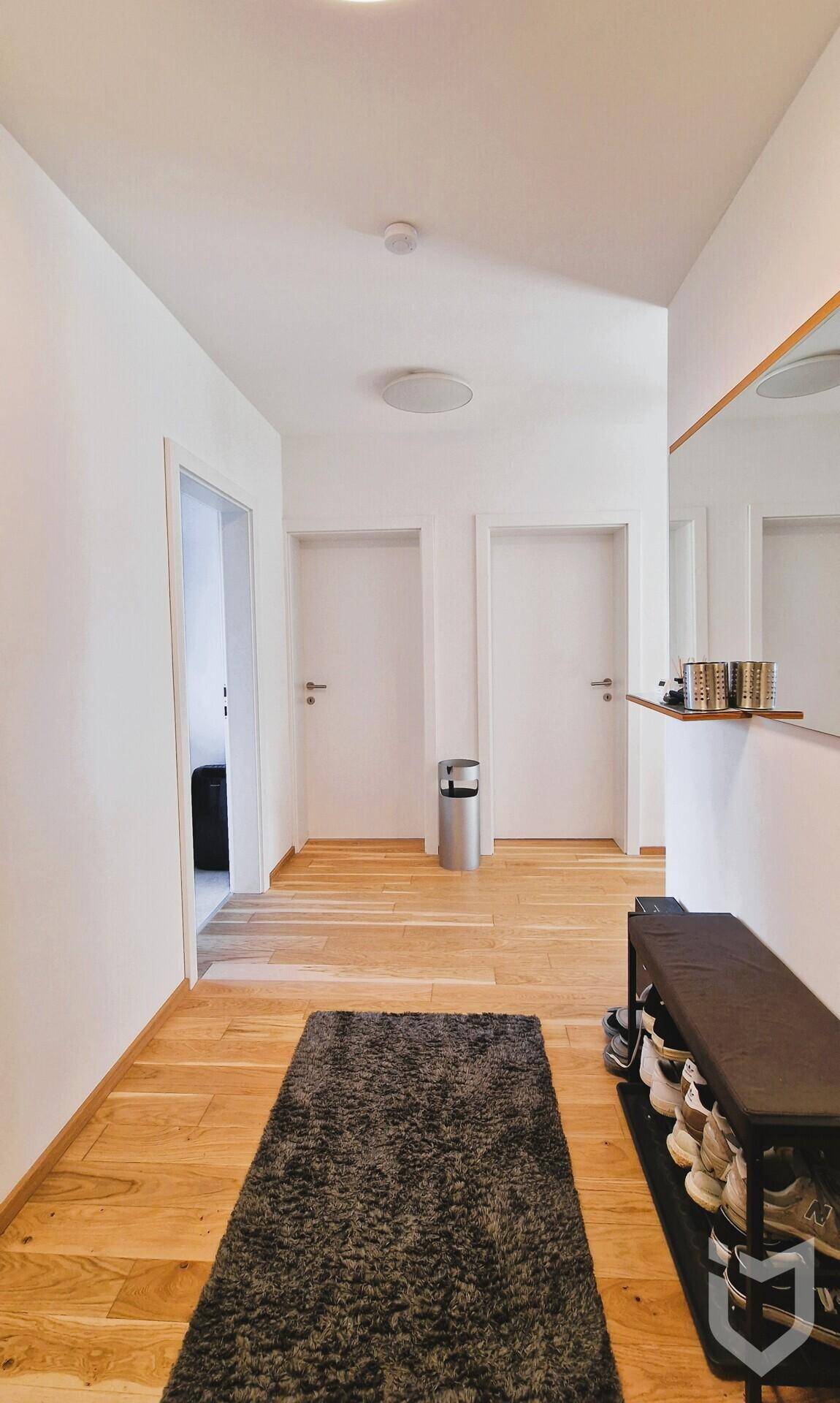Heller Eingangsbereich mit Holzboden, Garderobe und Schuhregal.