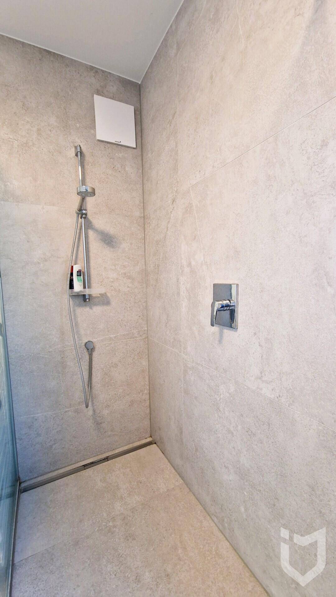Ebenerdige Dusche mit modernen Fliesen und Duscharmatur im Badezimmer.