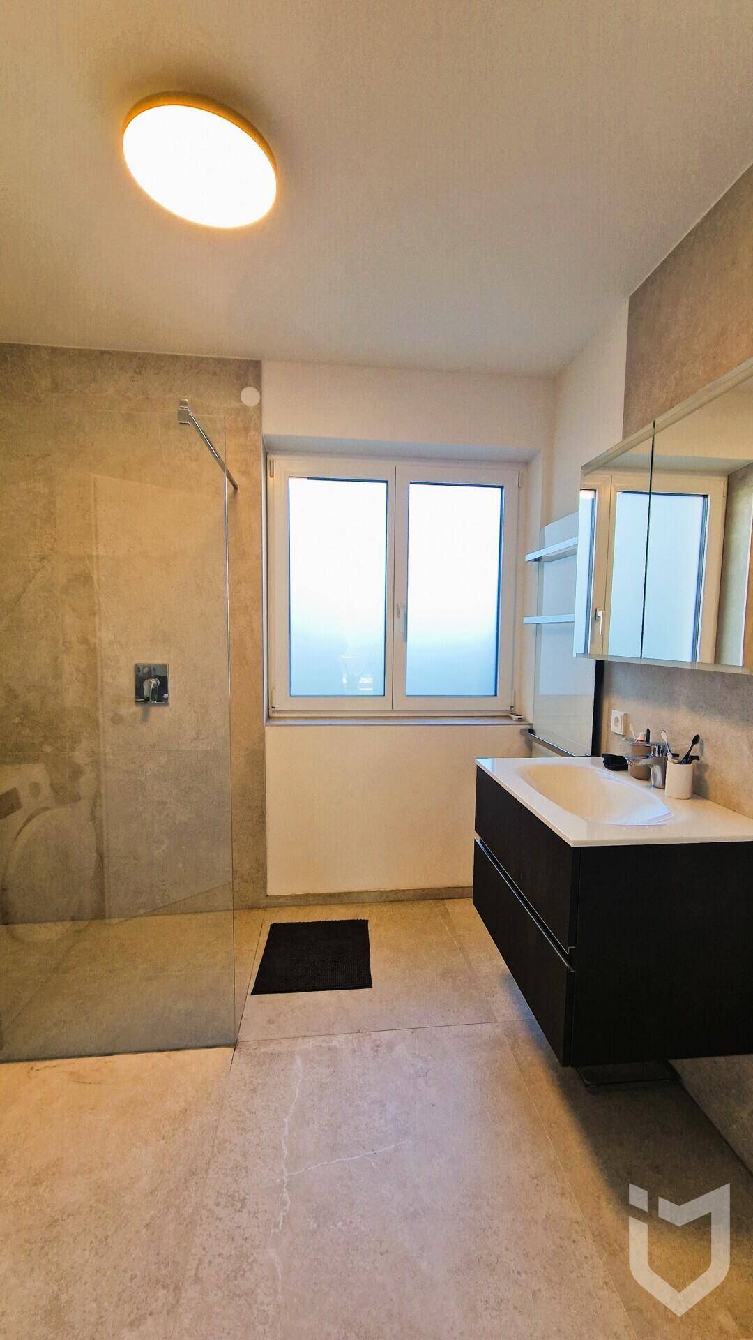 Modernes Badezimmer mit ebenerdiger Dusche, Waschtisch und Fenster.