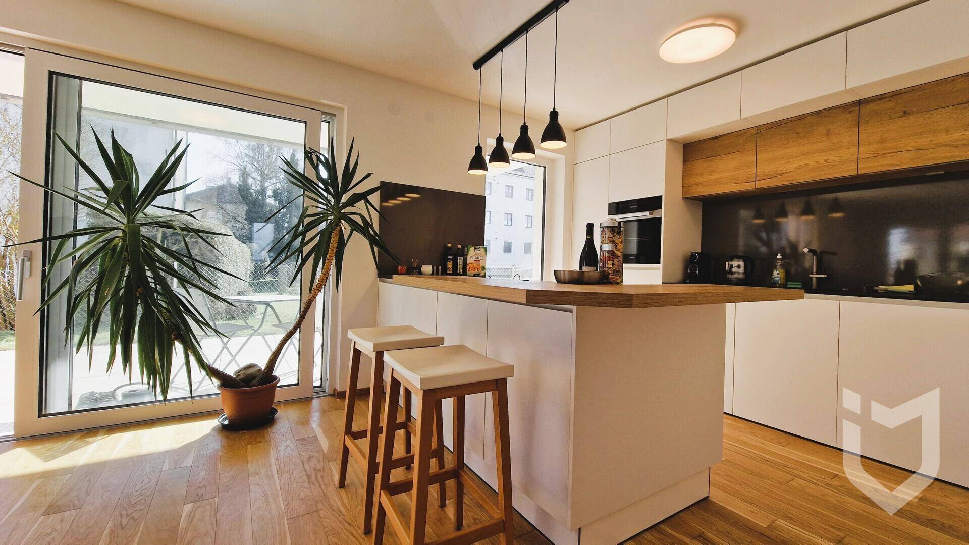 Moderne Küche mit Kochinsel, Holzboden und großem Fenster zum Garten.