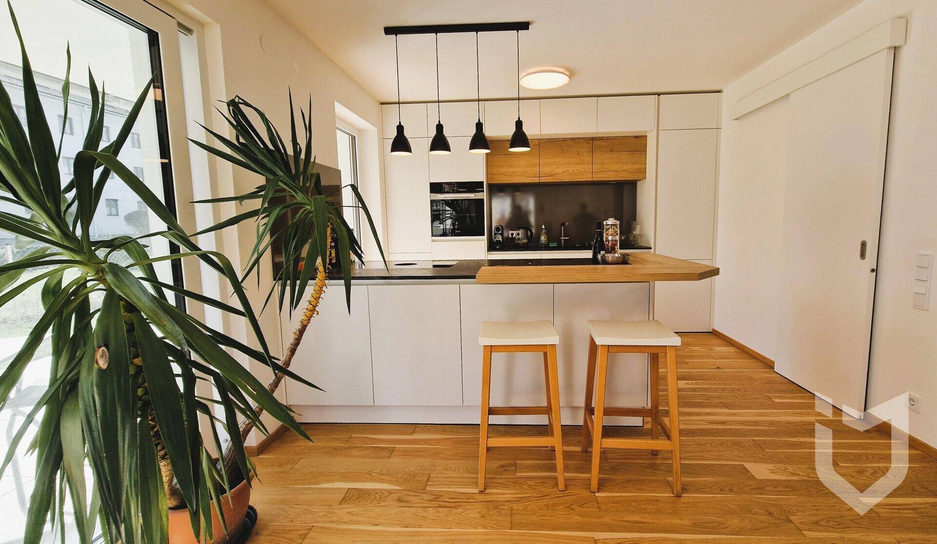 Helle, moderne Küche mit Kochinsel, Holzboden und Zugang zum Außenbereich.