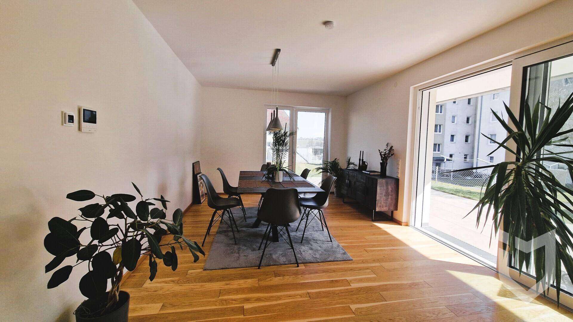 Geräumiger Wohn-Essbereich mit Holzboden, Esstisch und großen Fenstern zum Garten.