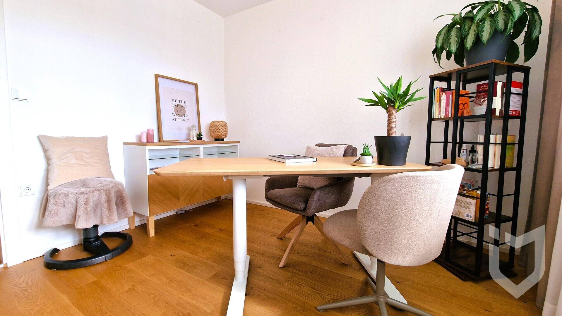 Helles Arbeitszimmer mit modernem Schreibtisch, Stühlen und einem Bücherregal.