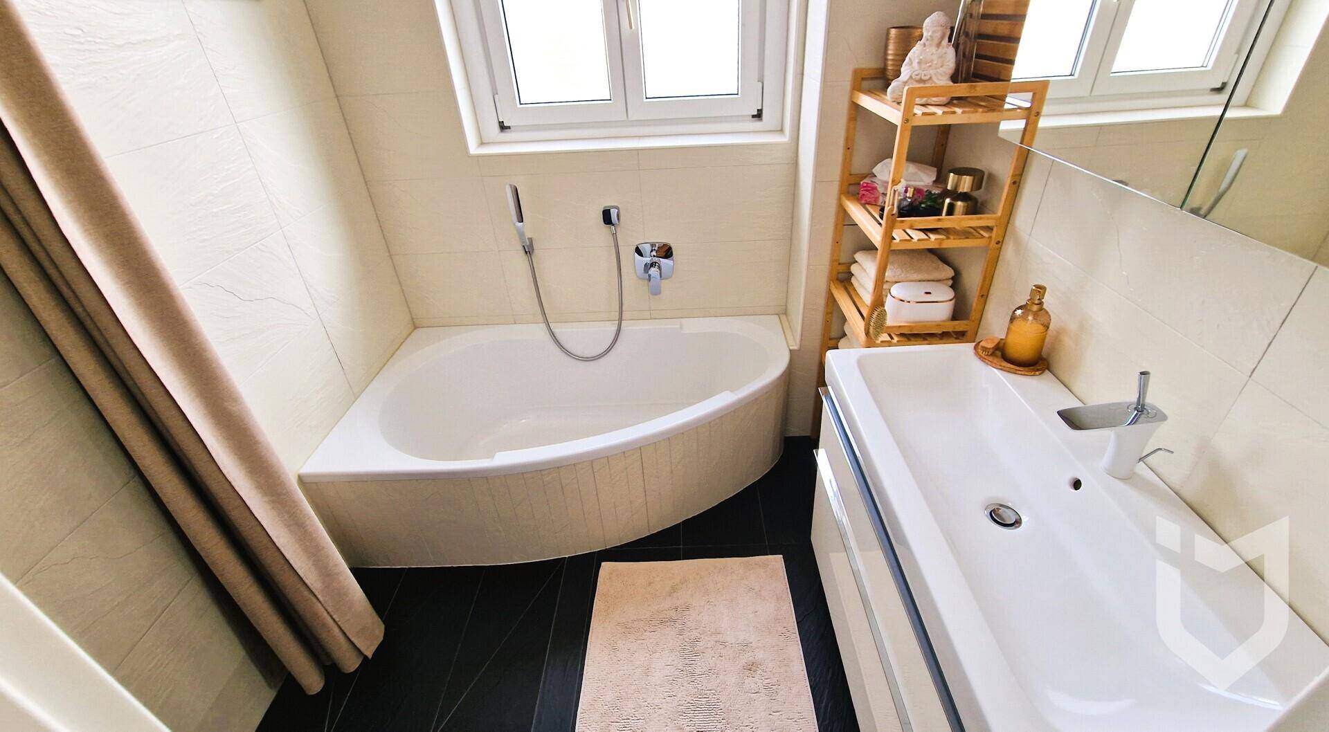 Modernes Badezimmer mit Eckbadewanne, Waschbecken und einem Fenster für Tageslicht.