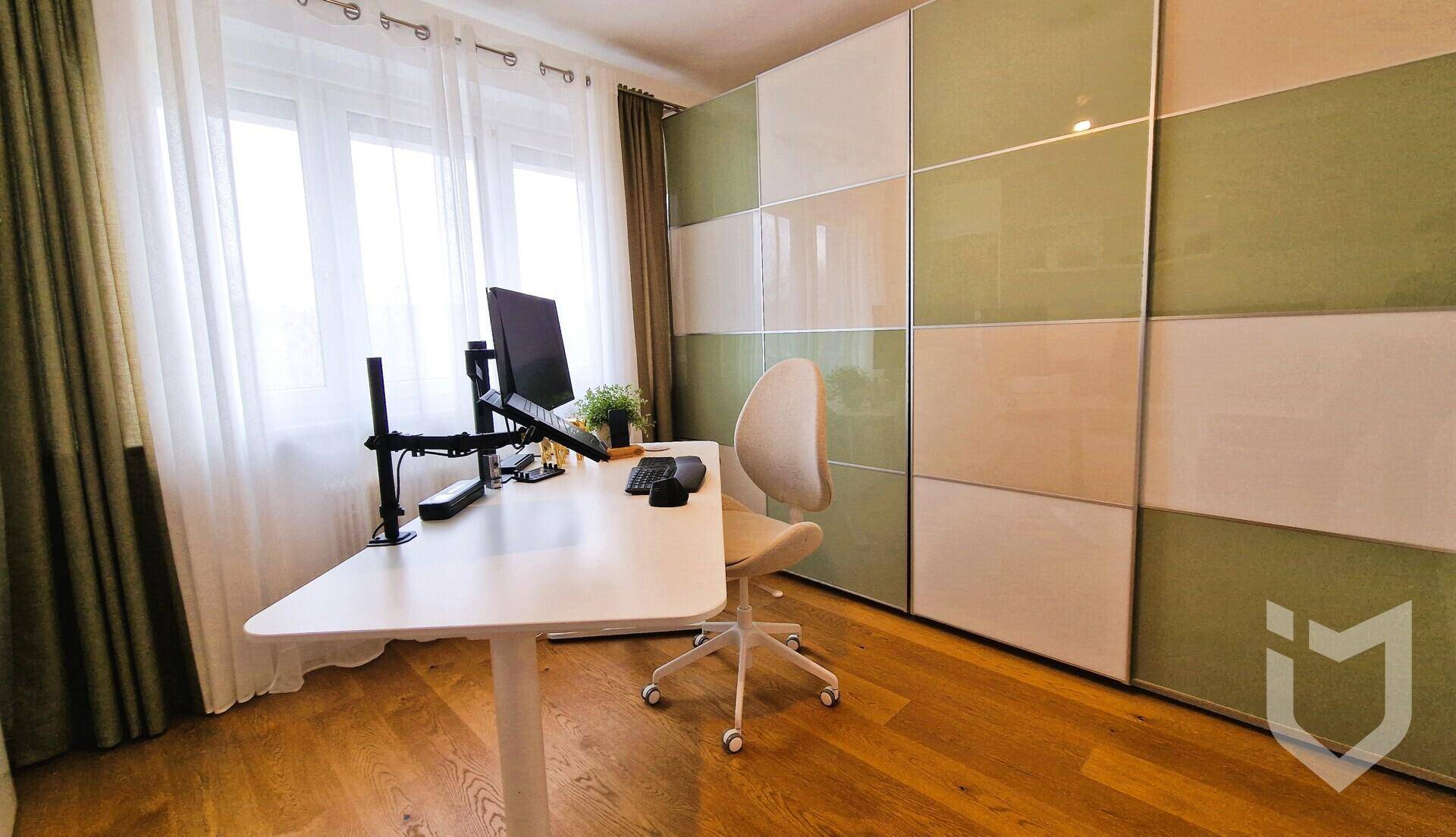 Arbeitszimmer mit Schreibtisch, Computer und einem großen, farbigen Einbauschrank.