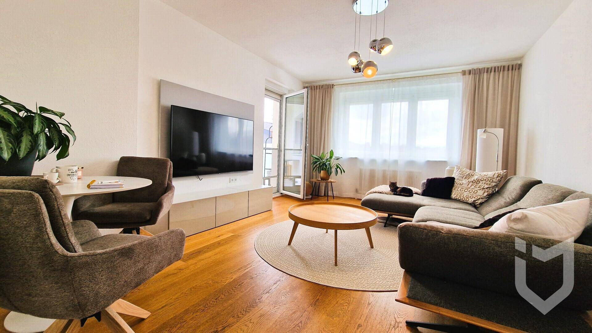 Helles Wohnzimmer mit modernem Sofa, Holzboden und Zugang zu einer Loggia.