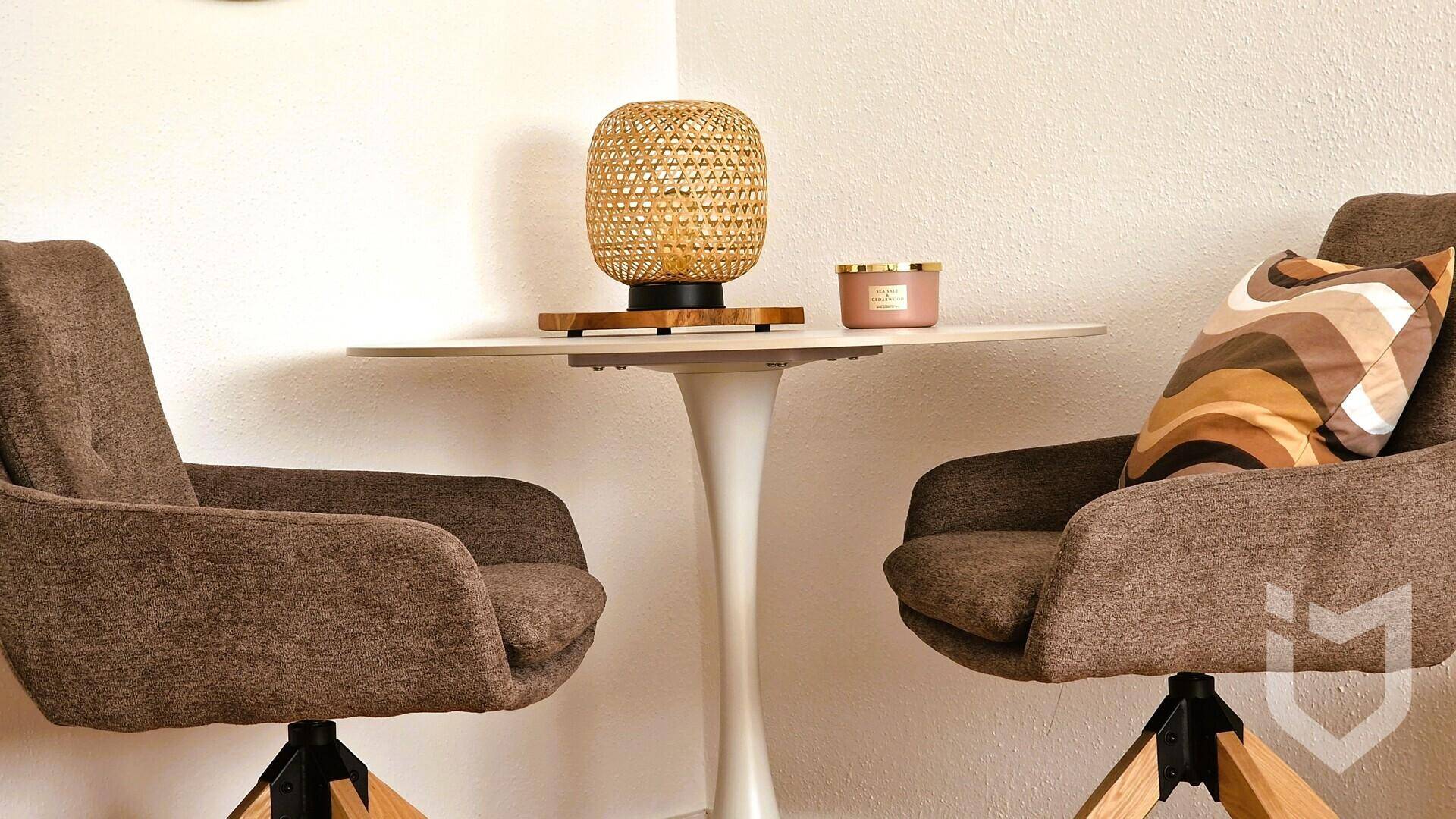 Detailaufnahme von zwei bequemen Sesseln und einem kleinen Beistelltisch im Wohnzimmerbereich.