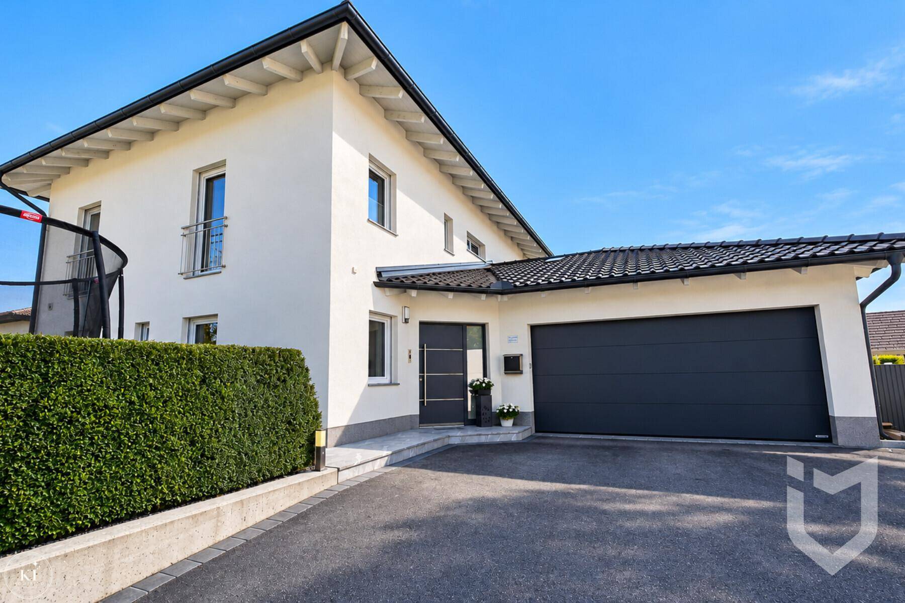 Vorderansicht des modernen Einfamilienhauses mit Doppelgarage und gepflegter Auffahrt.