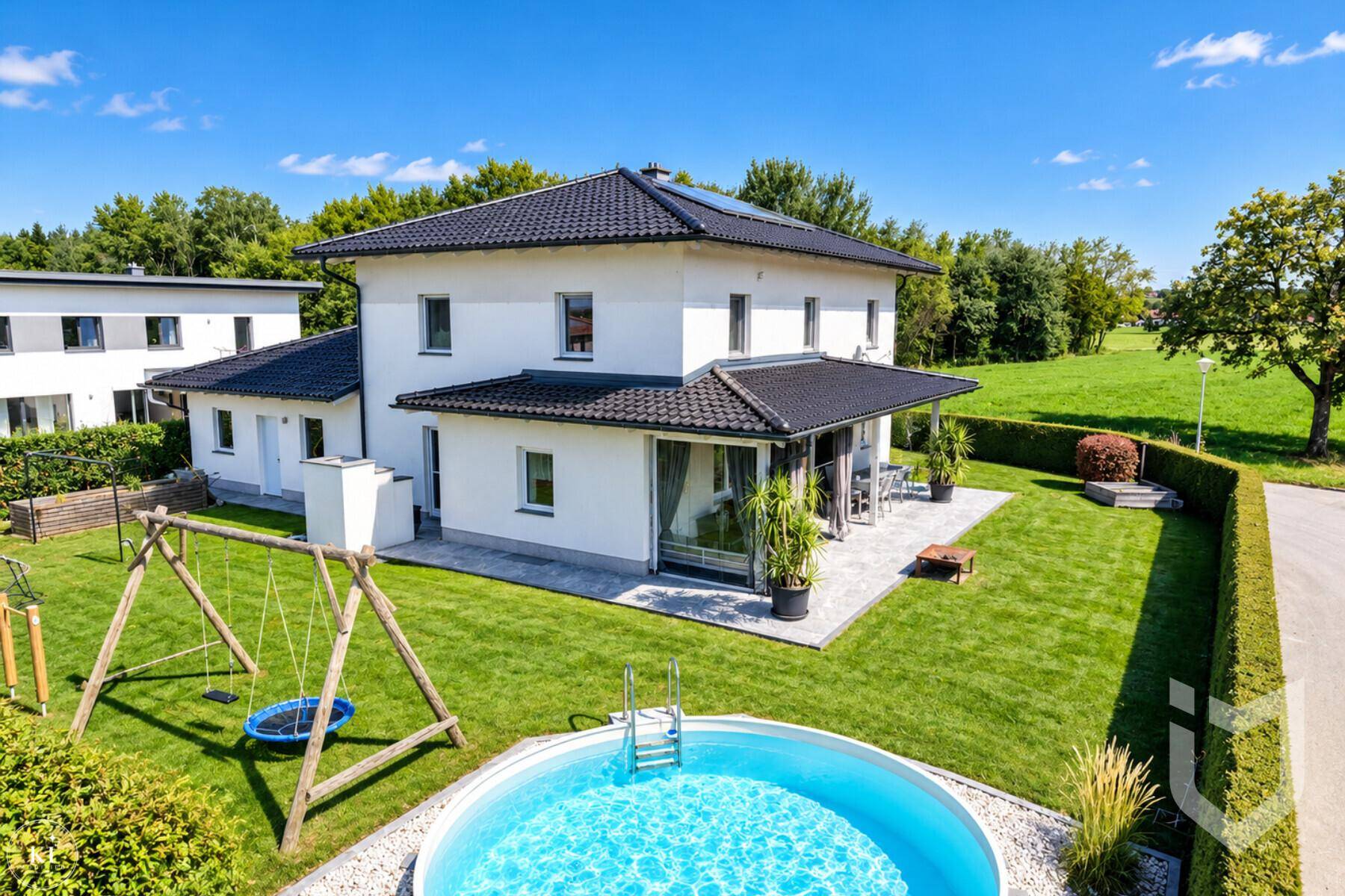 Gartenbereich mit rundem Pool, Schaukel und großer Terrasse hinter dem Einfamilienhaus.