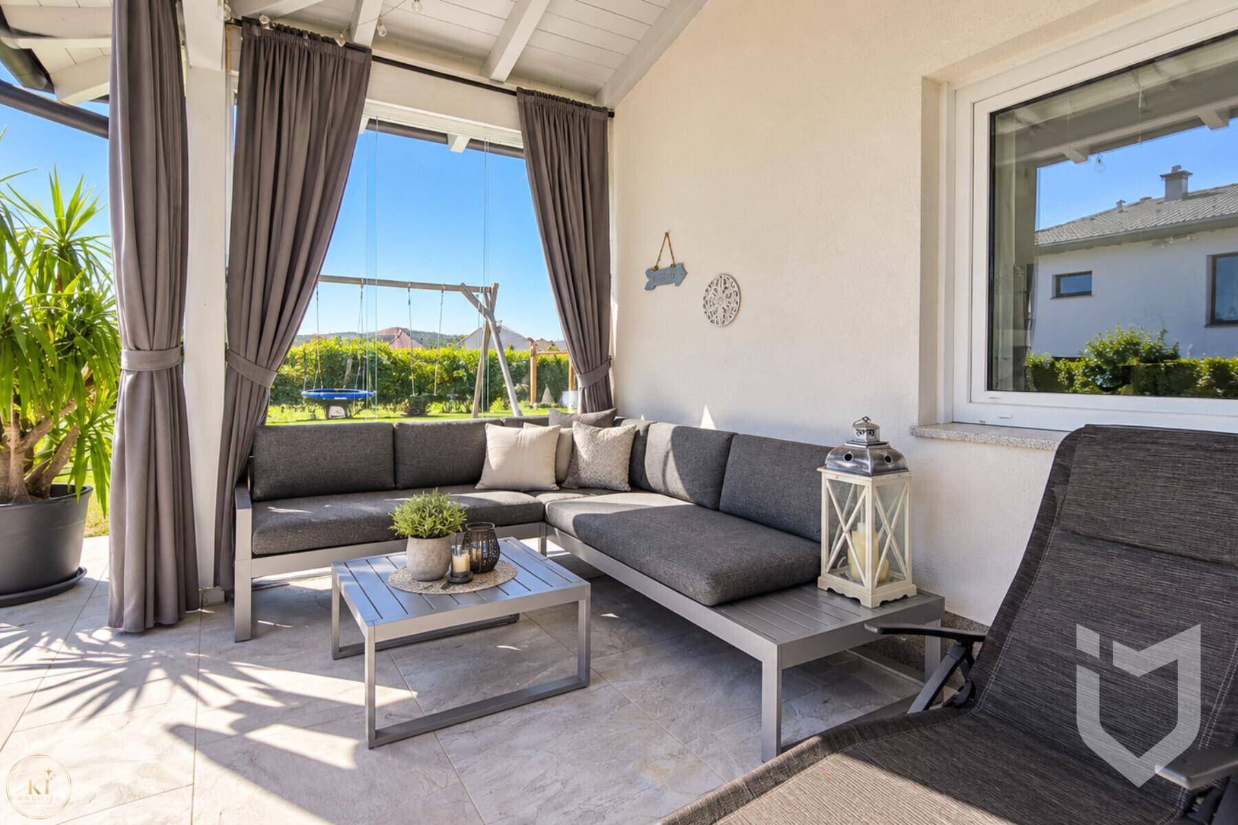 Gemütliche überdachte Terrasse mit bequemen Lounge-Möbeln und Blick ins Grüne.
