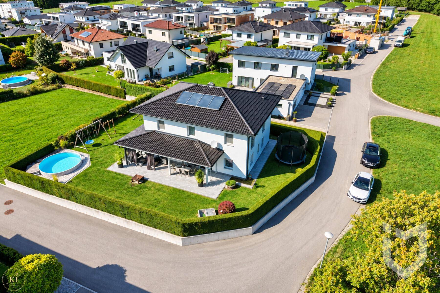 Luftaufnahme des Einfamilienhauses mit Garten, Pool und umliegender Wohnsiedlung.