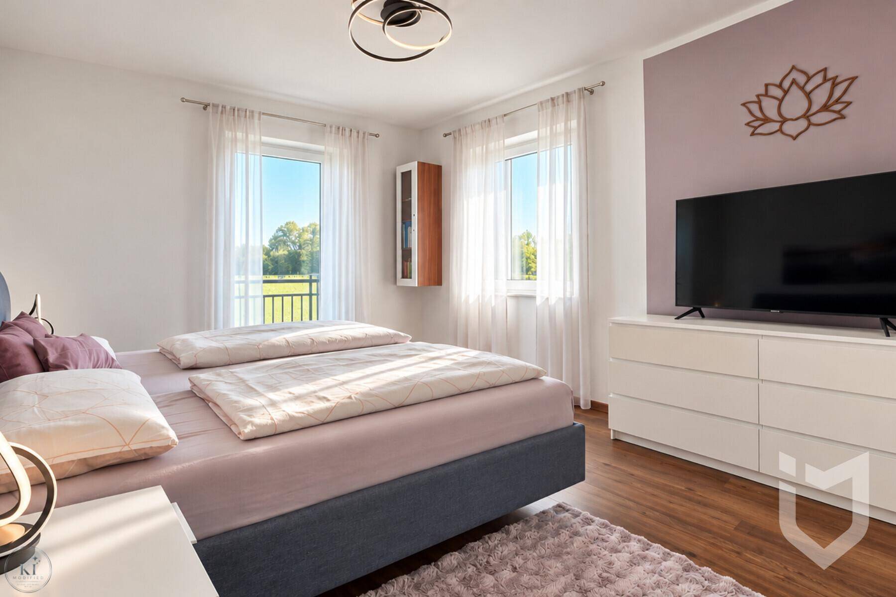 Schlafzimmer mit Doppelbett, hellem Interieur und Zugang zu einem französischen Balkon.