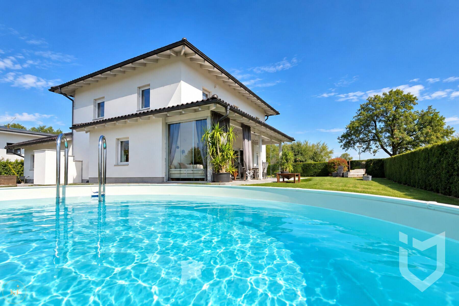 Blick auf das Haus vom Pool aus, umgeben von grünem Rasen und Bäumen.