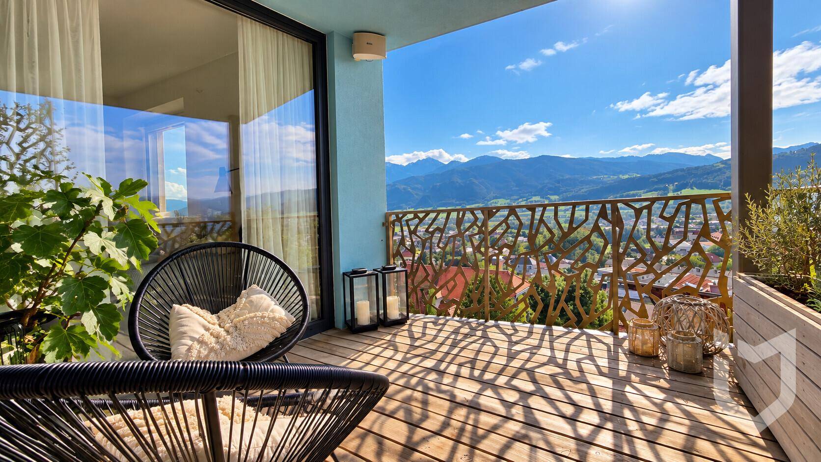 Sonniger Balkon mit Sitzgelegenheiten und weitem Blick auf die Berge und das Tal.