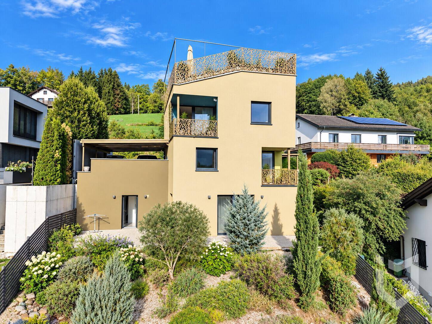 Ansicht der modernen Fassade des Hauses mit Terrassen und üppiger Bepflanzung.