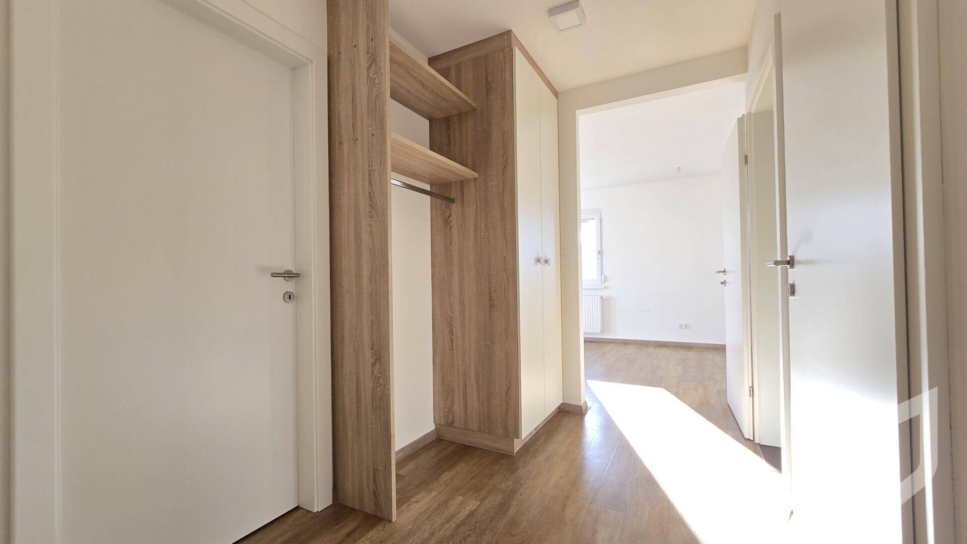 Heller Flur mit integriertem Garderobenschrank und Laminatboden, der zu weiteren Räumen führt.