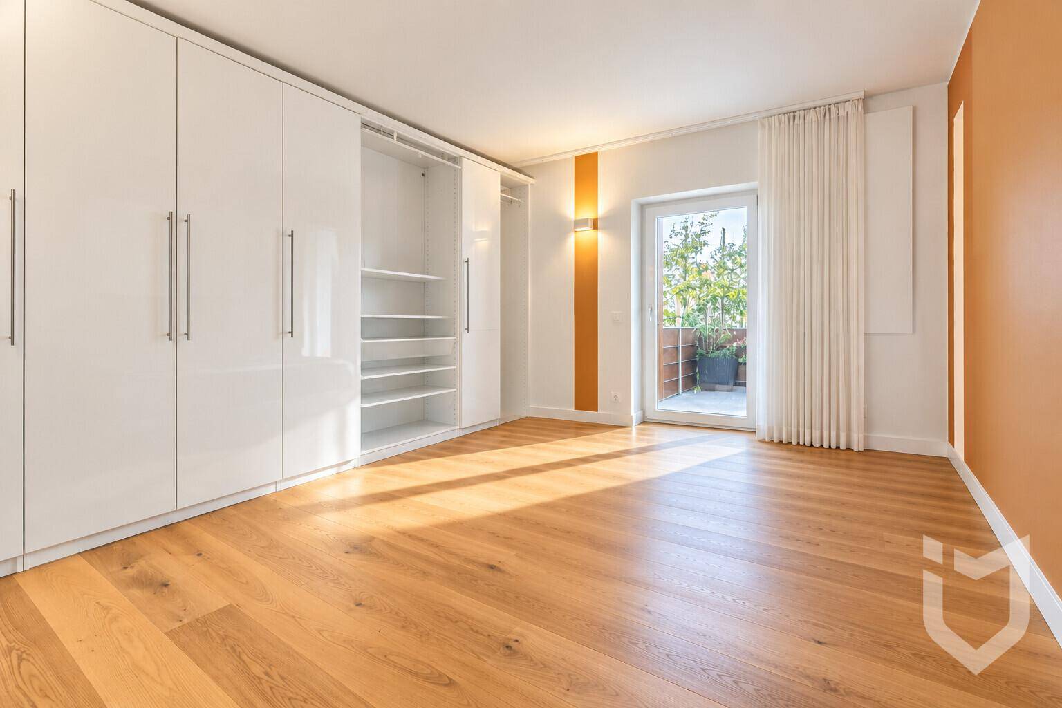 Geräumiges Schlafzimmer mit Einbauschränken, Parkettboden und Balkonzugang.