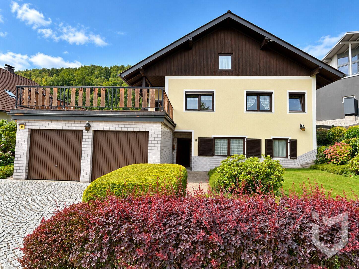 Vorderansicht des Einfamilienhauses mit Doppelgarage und üppiger Bepflanzung im Vorgarten.