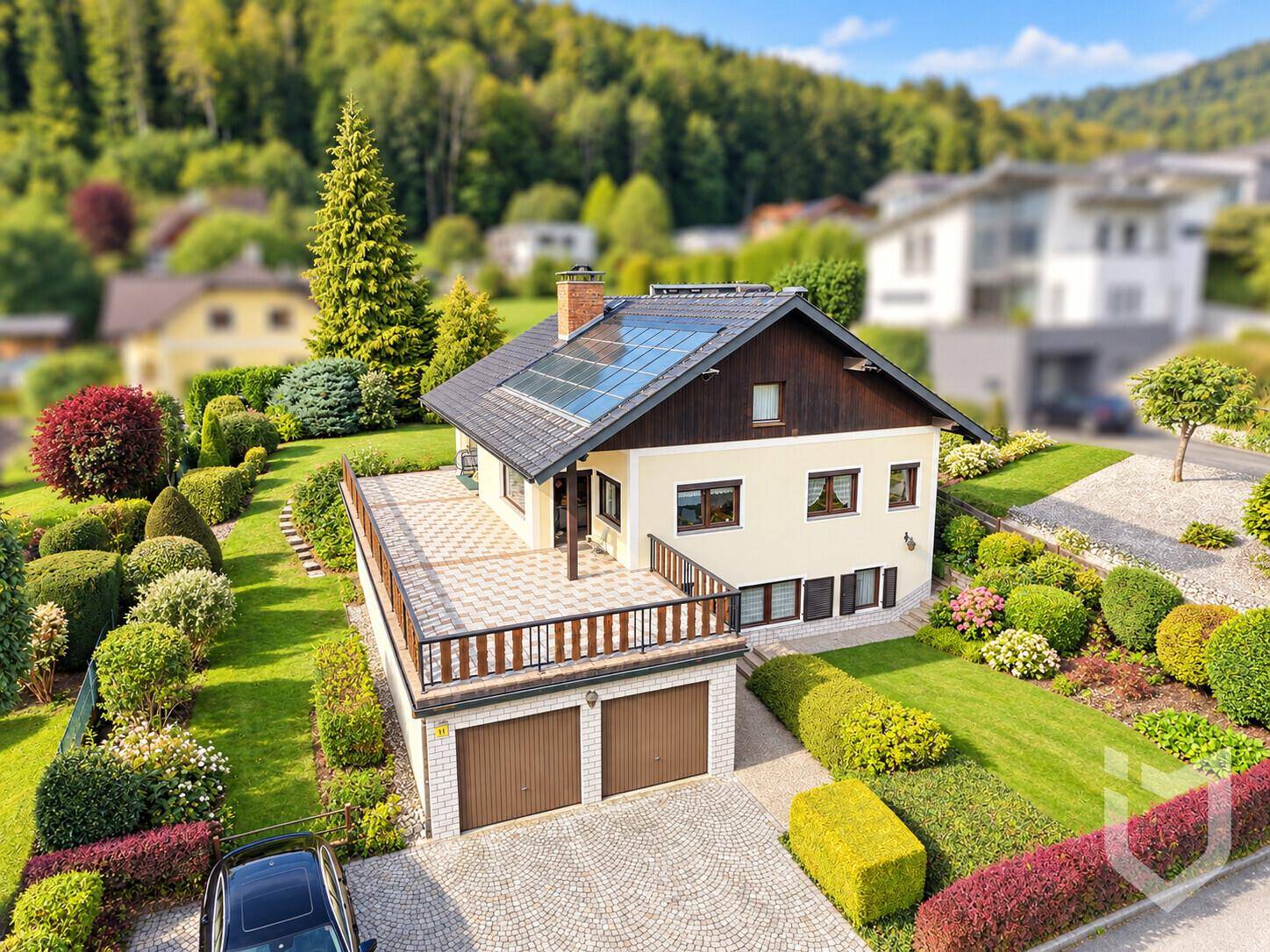 Luftaufnahme eines Einfamilienhauses mit Photovoltaikanlage auf dem Dach und gepflegtem Garten.
