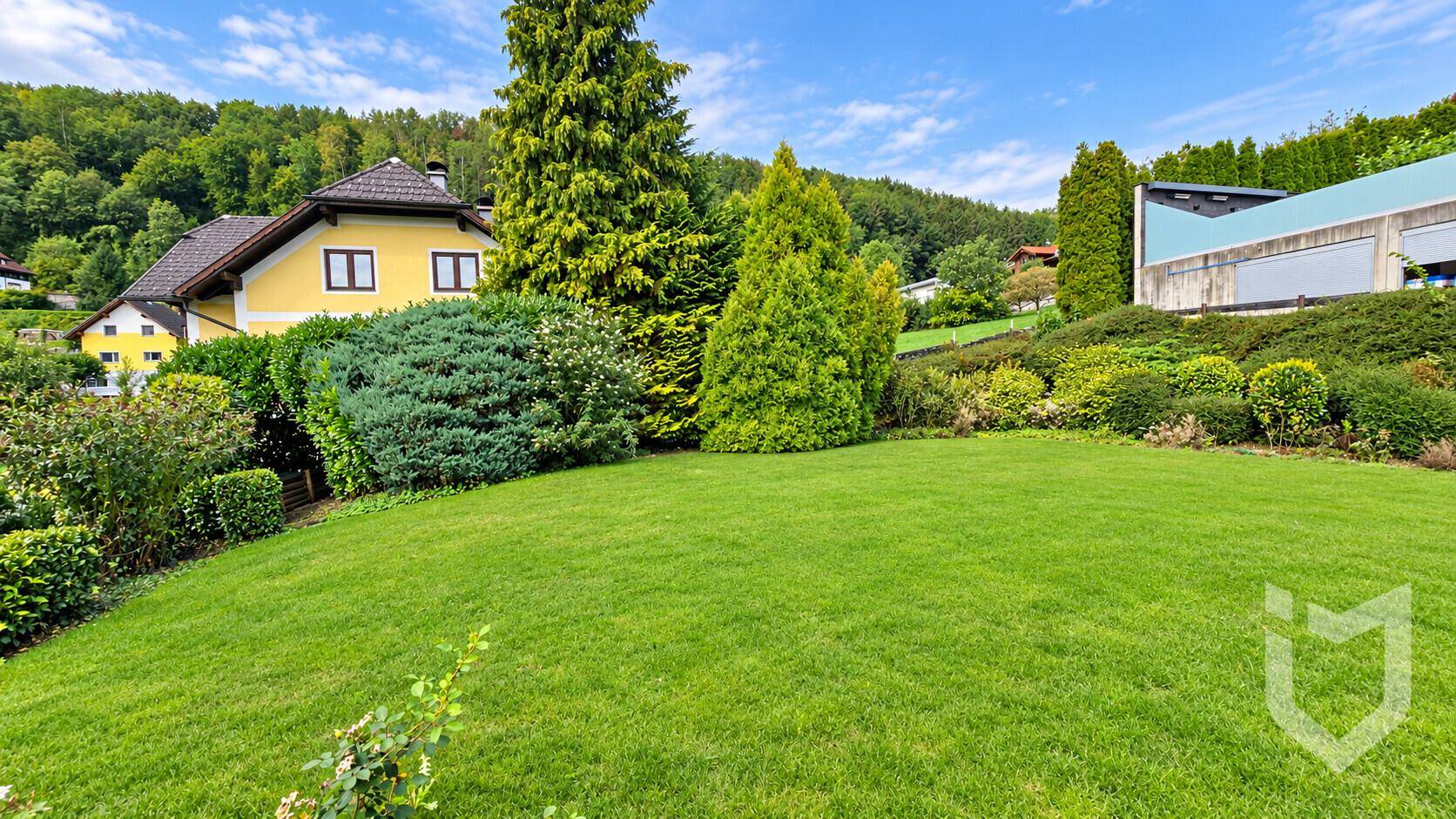 Weitläufiger Gartenbereich mit gepflegtem Rasen und Blick auf das Einfamilienhaus im Hintergrund.