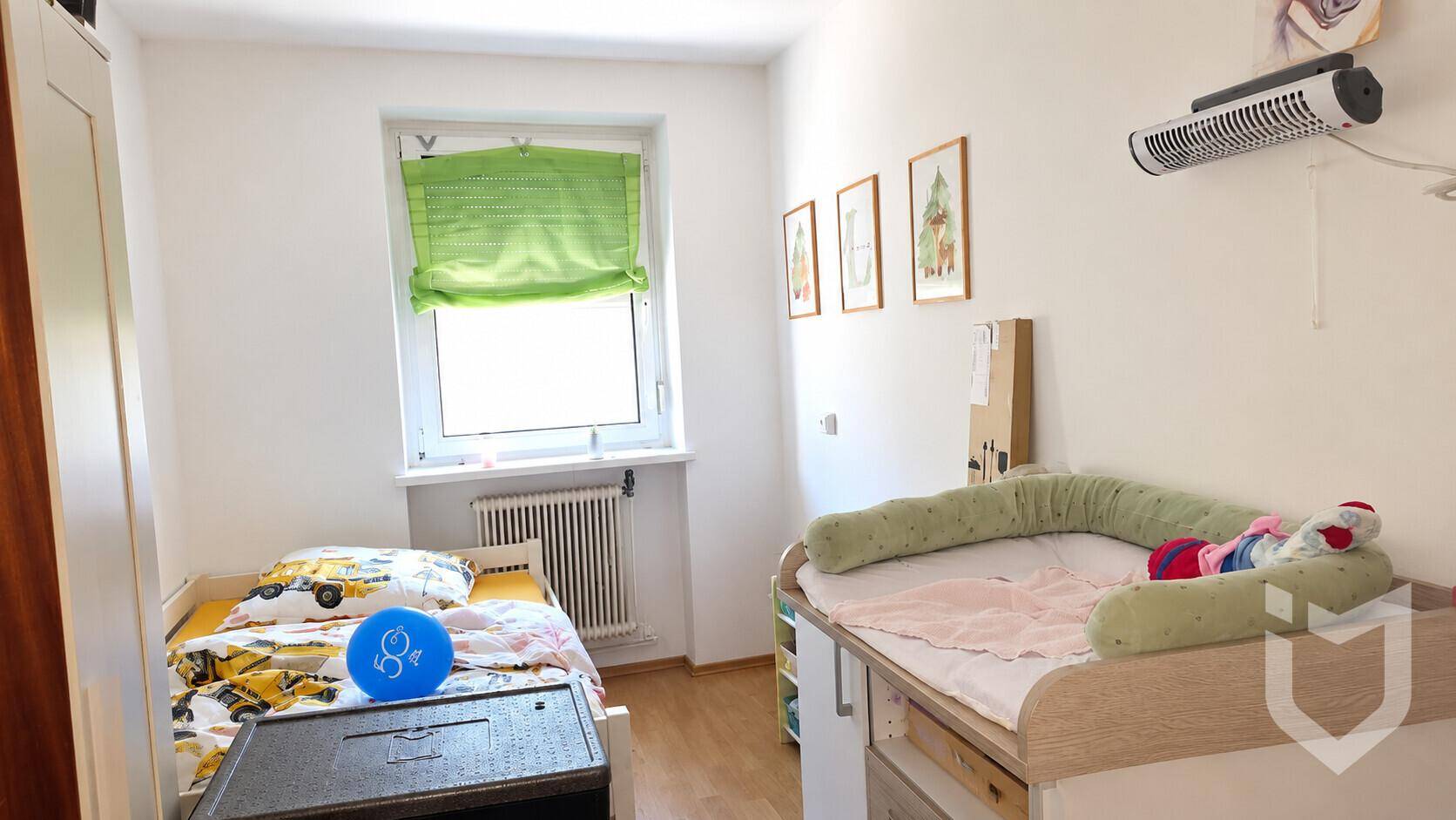 Kinderzimmer mit Einzelbett, Wickeltisch und Fenster, hell und funktional eingerichtet.