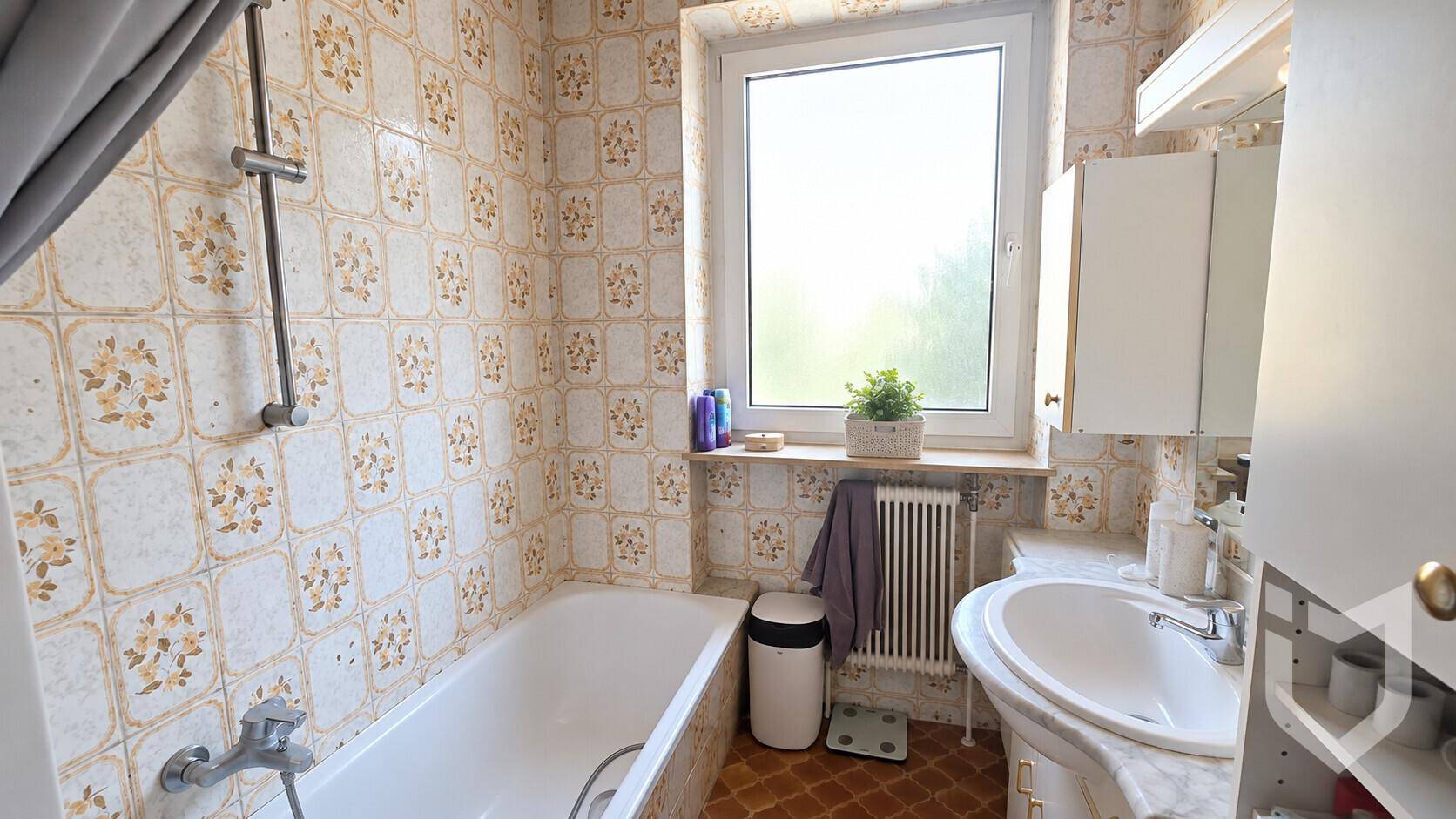 Badezimmer mit Badewanne, Waschbecken und Fenster, gefliest im Vintage-Stil der 80er Jahre.