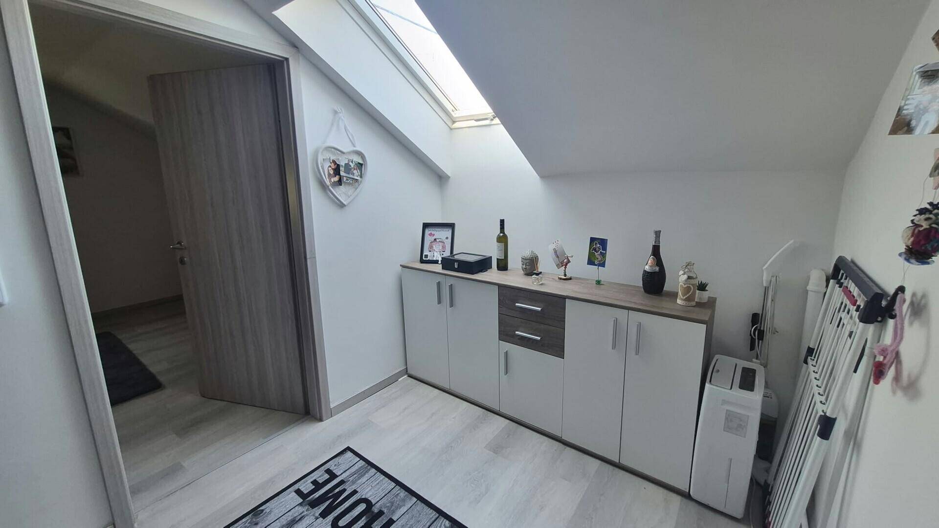 Heller Flurbereich im Dachgeschoss mit Dachfenster und praktischen Aufbewahrungsschränken.