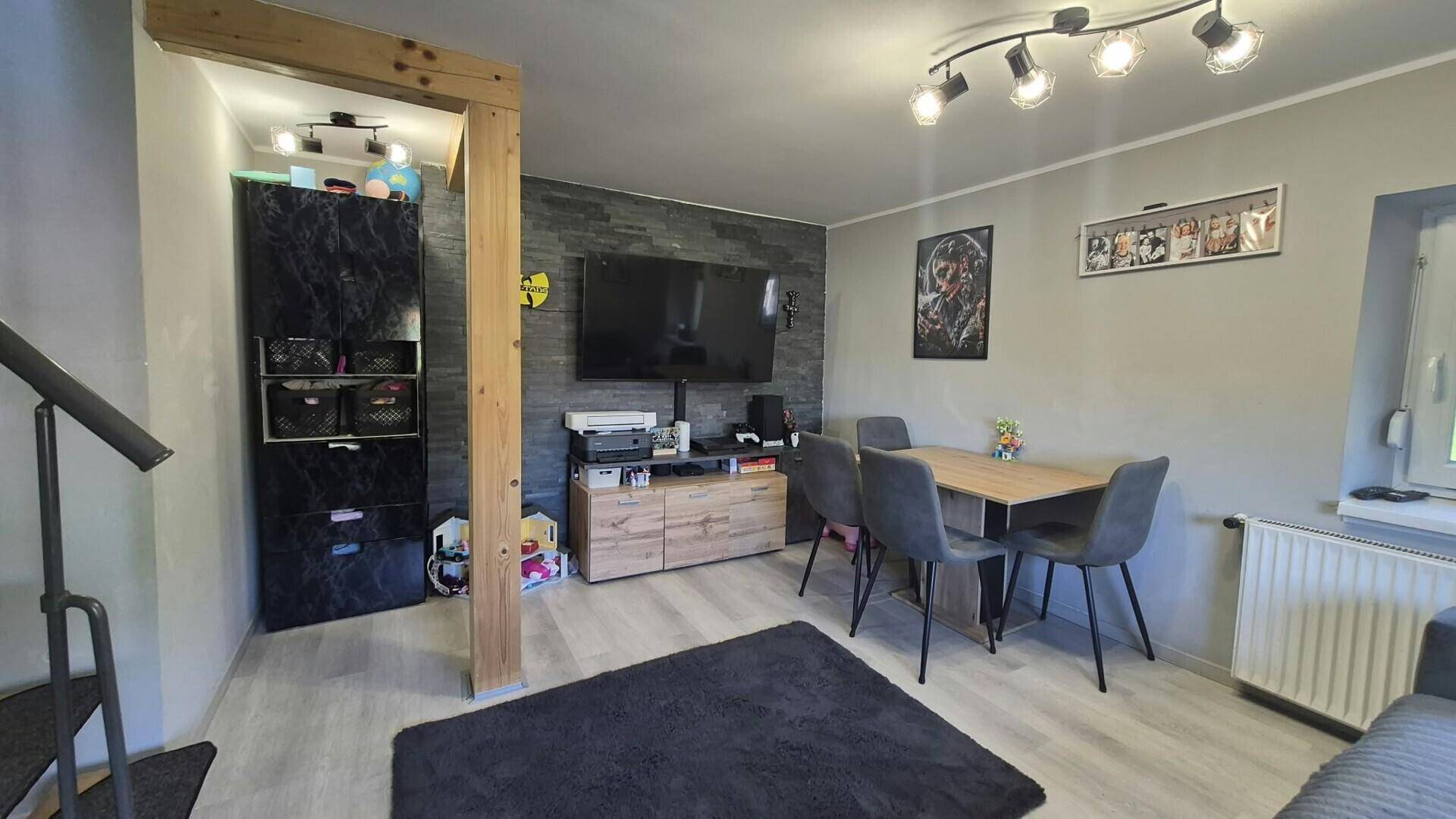 Gemütlicher Wohn-Essbereich mit Esstisch, Fernseher und modernem Laminatboden.