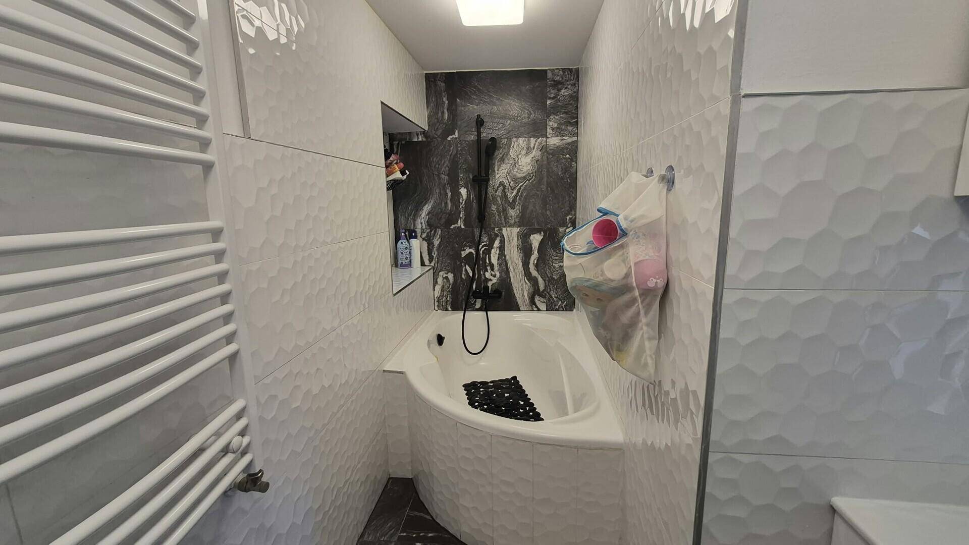 Modernes Badezimmer mit Eckbadewanne und stilvollen weißen Wandfliesen.