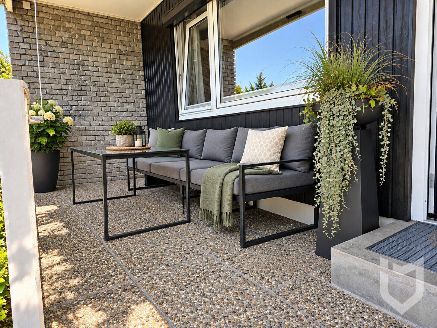 Gemütliche Terrasse mit moderner Sitzgelegenheit, Pflanzen und Kiesboden für entspannte Stunden im Freien.