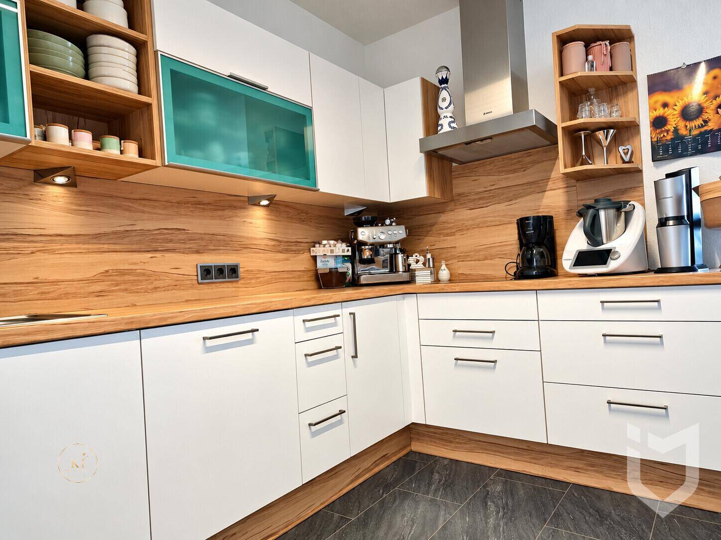 Moderne Küche mit weißen Schränken, Holz-Arbeitsplatten und integrierten Geräten.