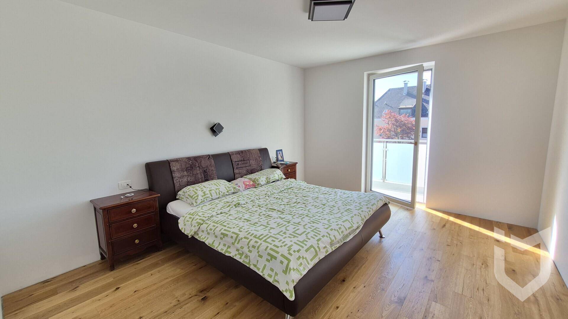 Gemütliches Schlafzimmer mit Doppelbett, Holzboden und Balkonzugang.