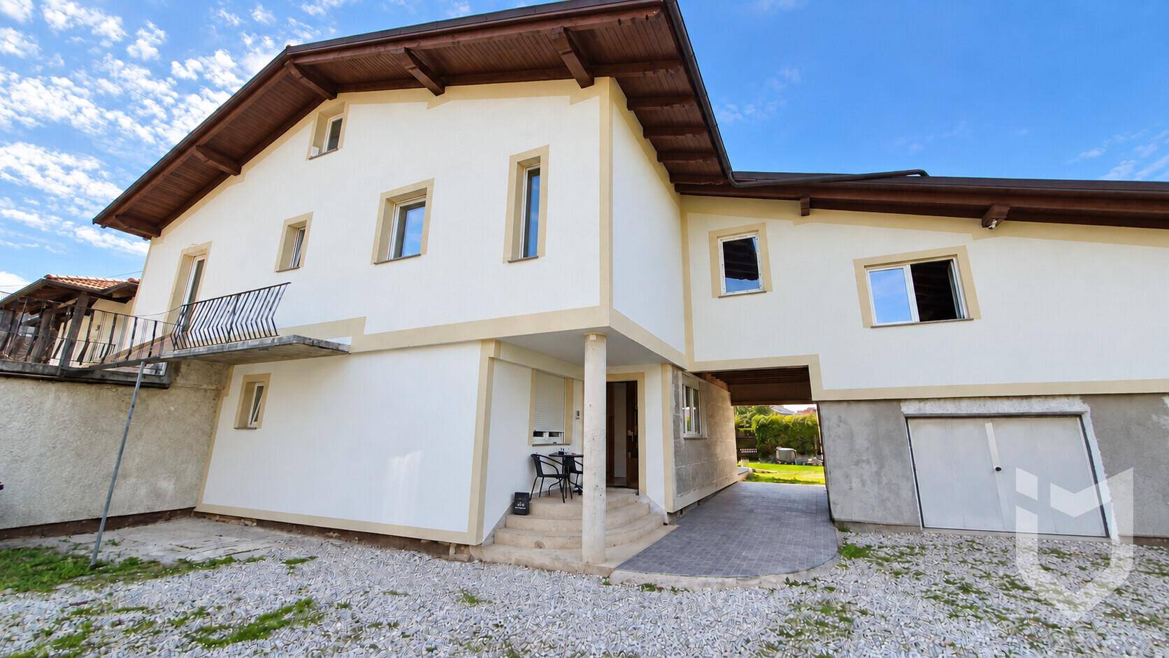 Rückseite des Hauses mit überdachtem Eingangsbereich und Kiesfläche.