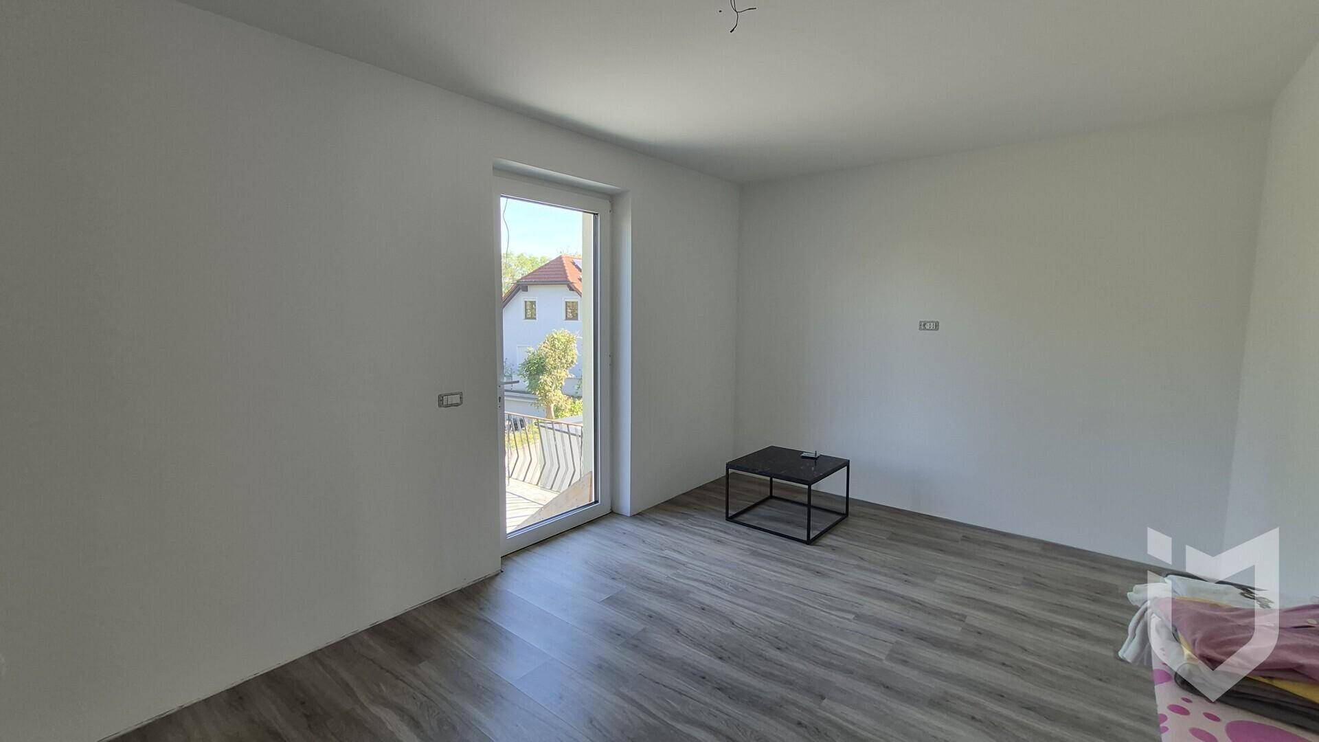 Heller Raum mit Laminatboden und Zugang zu einem französischen Balkon.