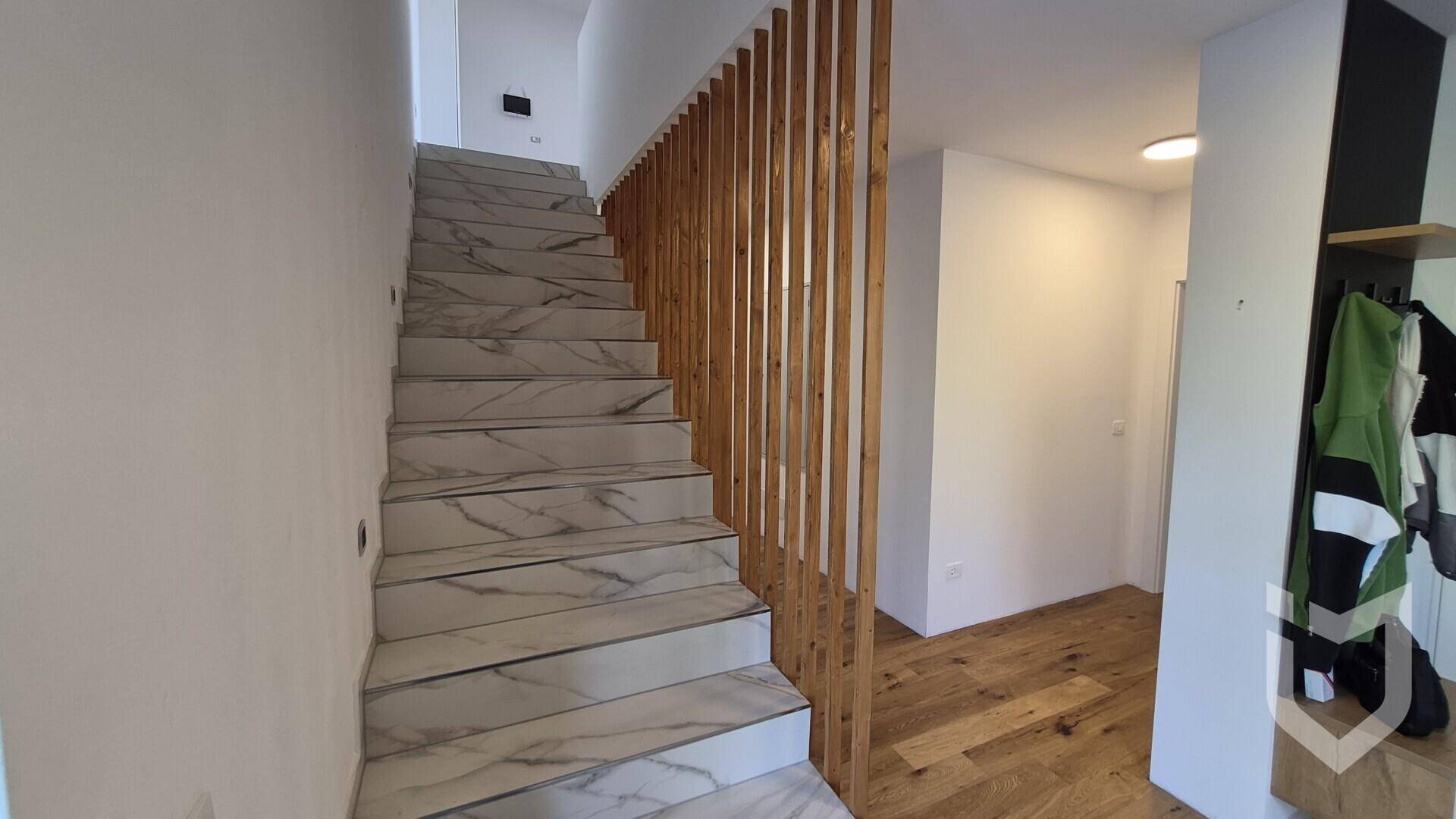Moderner Treppenaufgang mit Marmorfliesen und Holzlamellen als Geländer.