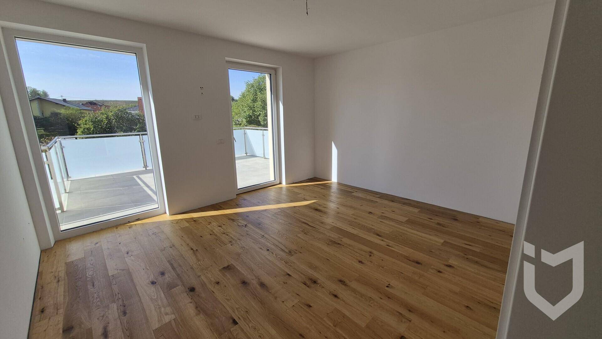 Geräumiges Schlafzimmer mit Holzboden und Zugang zu einem Balkon.
