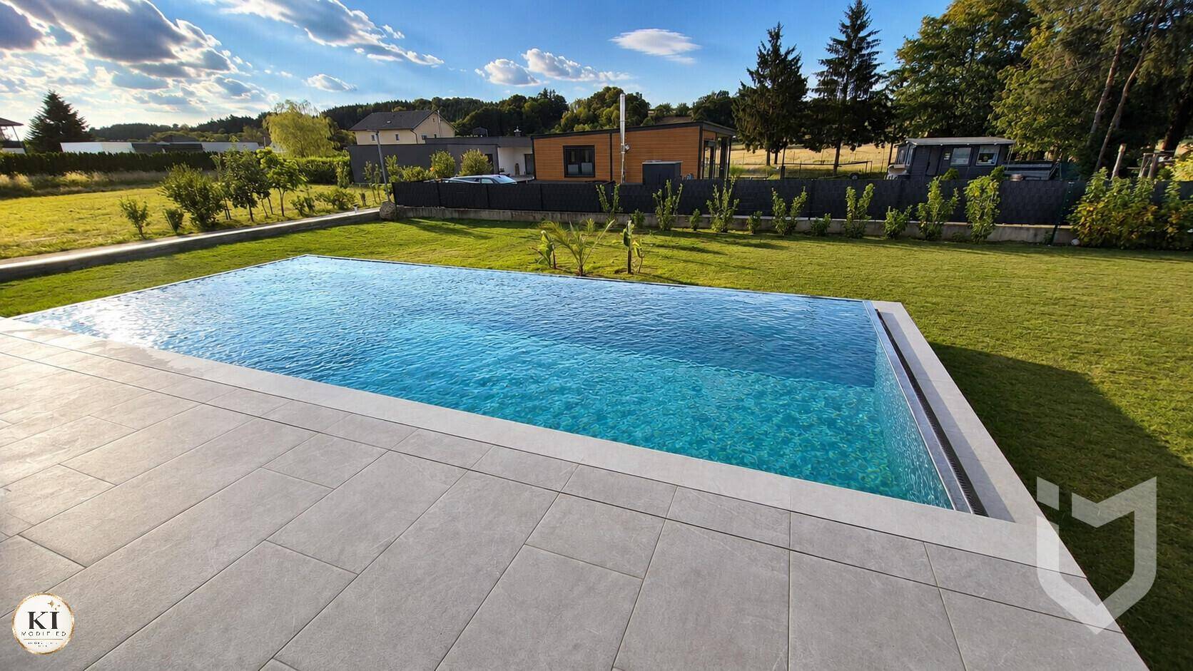 Großer Infinity-Pool im Garten mit umliegender Rasenfläche und weitem Blick in die Landschaft.