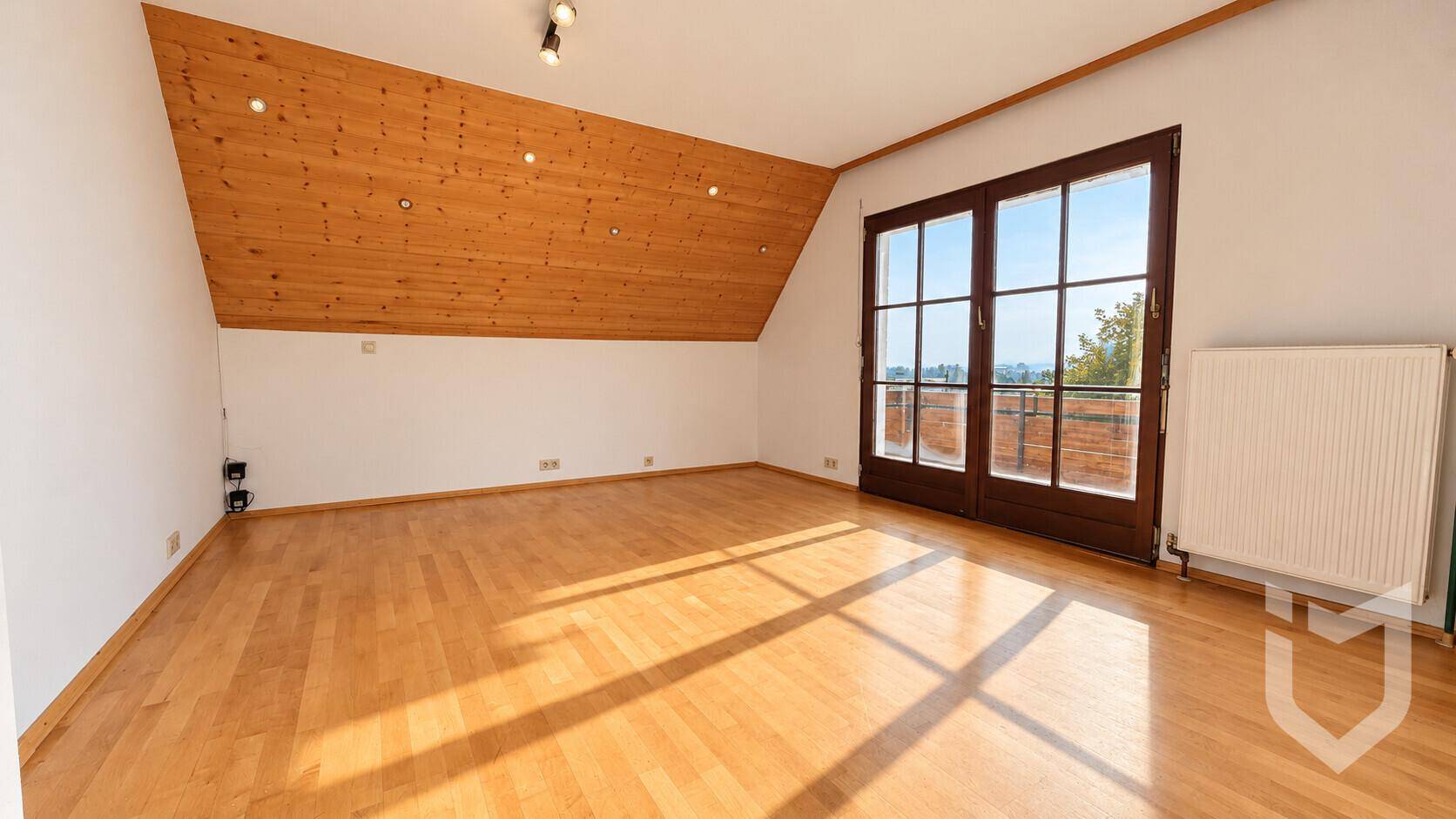 Helles Schlafzimmer mit Holzboden, Dachschräge und großen Fenstern.