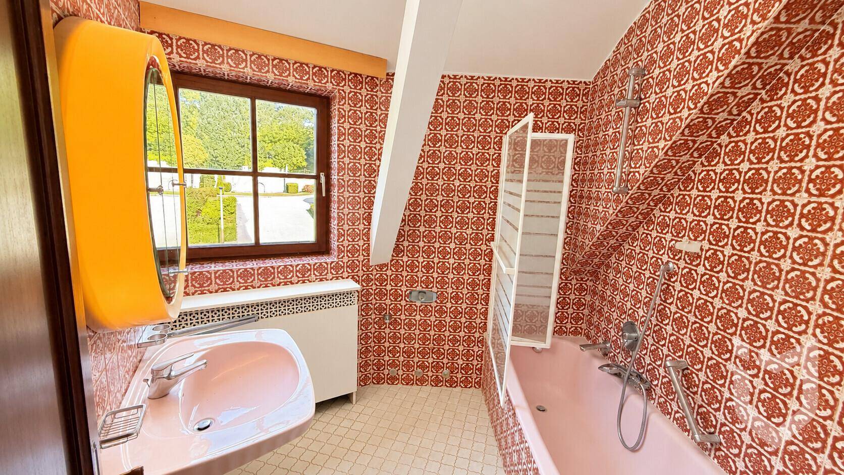 Badezimmer im 80er-Jahre-Stil mit gemusterten Fliesen und Badewanne.