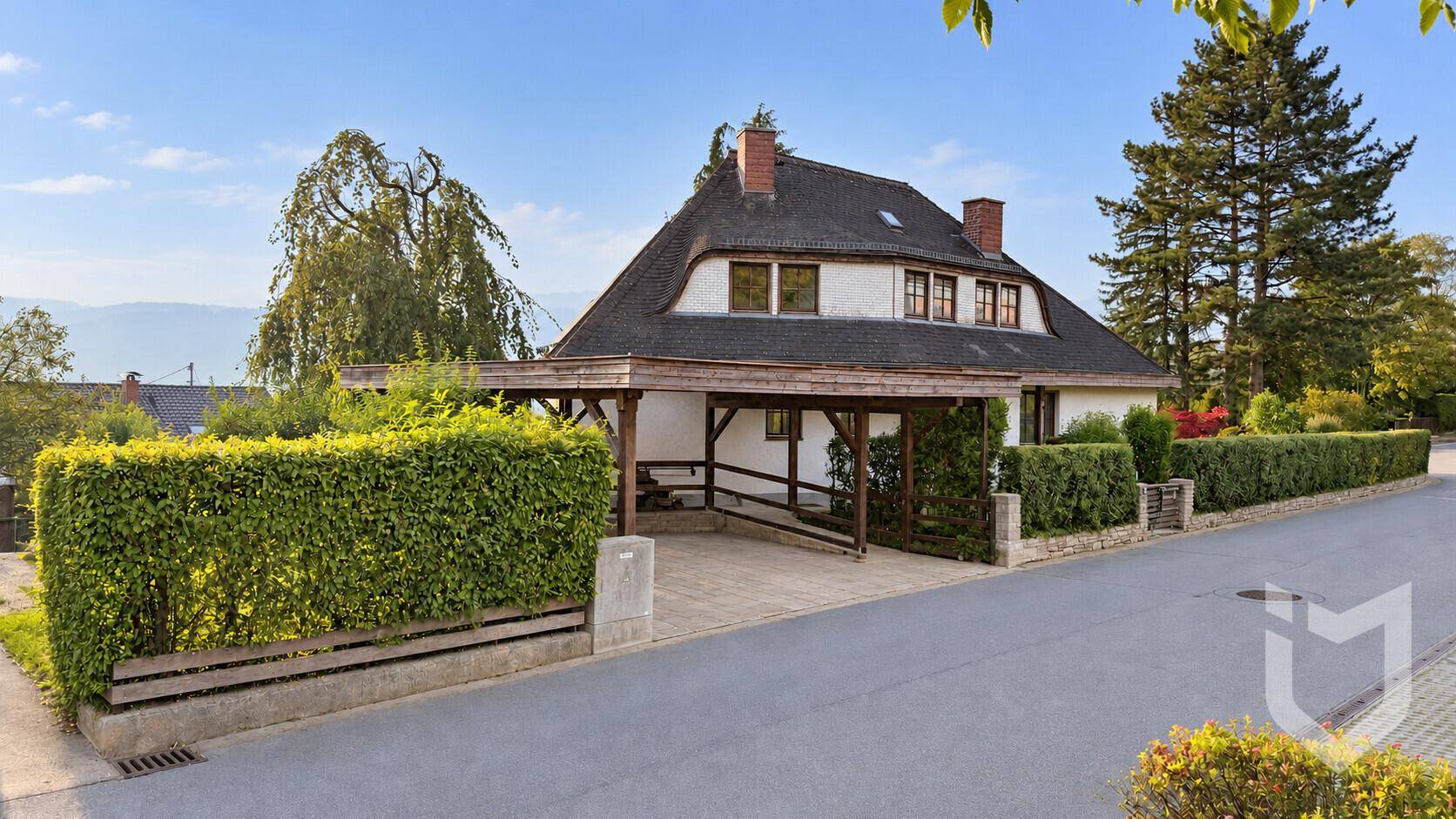 Einfamilienhaus mit Carport, gepflegtem Vorgarten und Zufahrt.