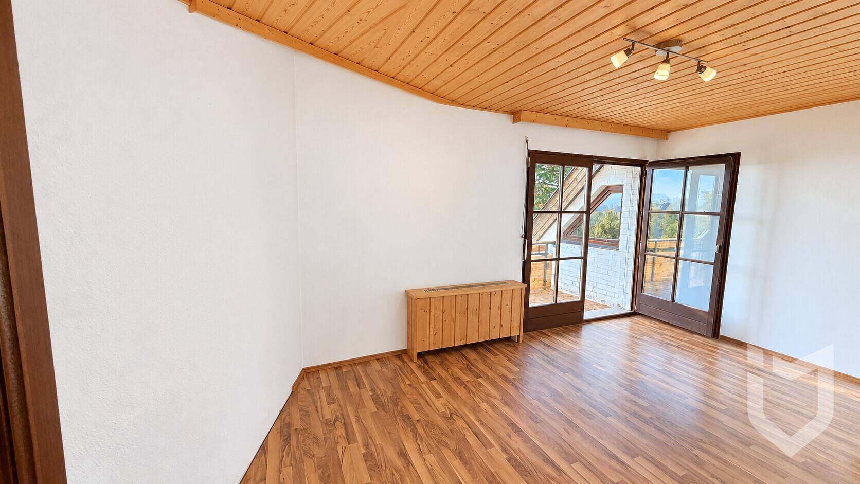Geräumiges Schlafzimmer mit Holzboden und Zugang zum Balkon.